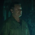 Steve Zahn as Solo/Jimmy looking hopeful in a dark, teal-lit industrial corridor in Silo.
