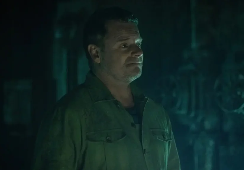 Steve Zahn as Solo/Jimmy looking hopeful in a dark, teal-lit industrial corridor in Silo.