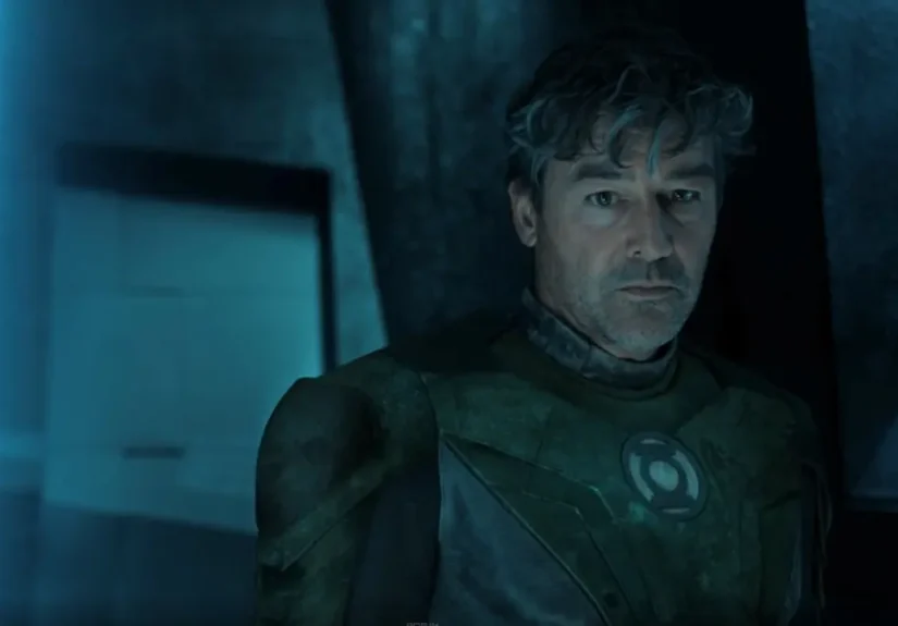 Kyle Chandler as Hal Jordan wearing a Green Lantern suit with a circular chest emblem under blue lighting.