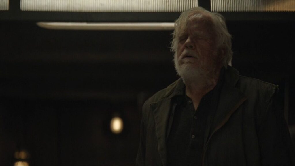 Steve Zahn as Solo/Jimmy standing with his eyes closed in a weary expression in Silo.