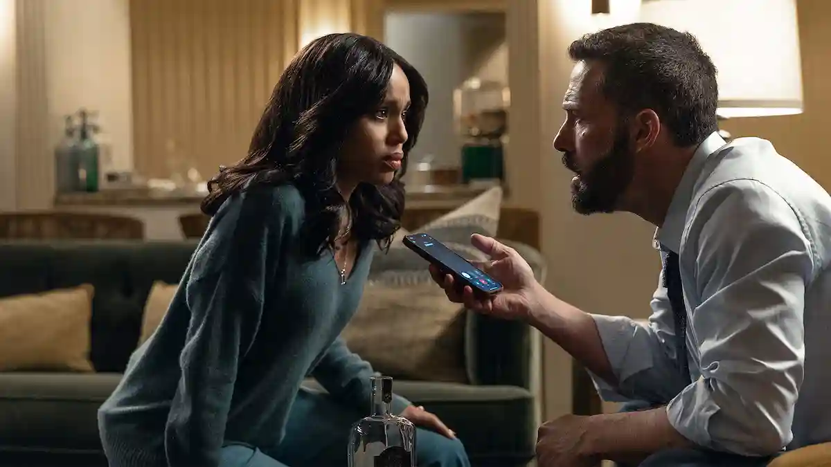Kerry Washington and Ben Affleck look intensely at a smartphone he is holding up in an indoor living room scene from the film Animals.