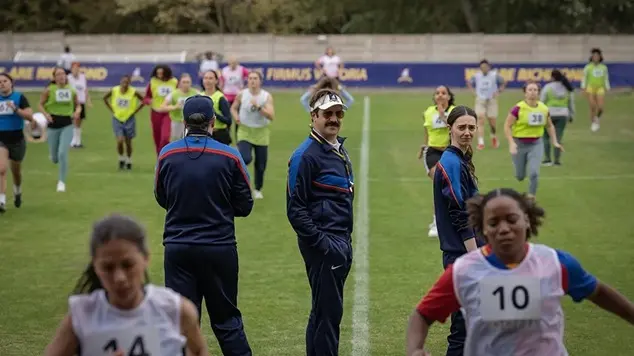 A first-look promotional photo from Season 4 of the Apple TV+ comedy series Ted Lasso, featuring Jason Sudeikis as Ted Lasso and Brendan Hunt as Coach Beard on a soccer field
