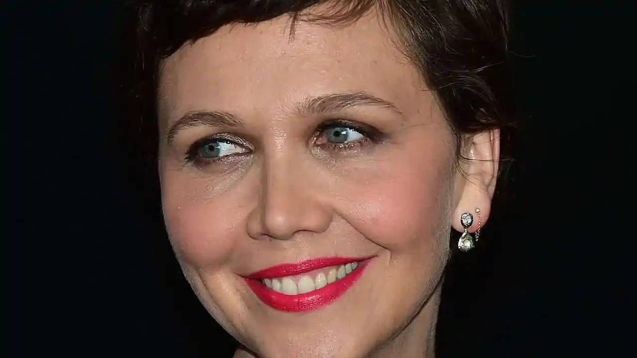 American actress Maggie Gyllenhaal with a short pixie haircut, red lipstick, and small earrings.